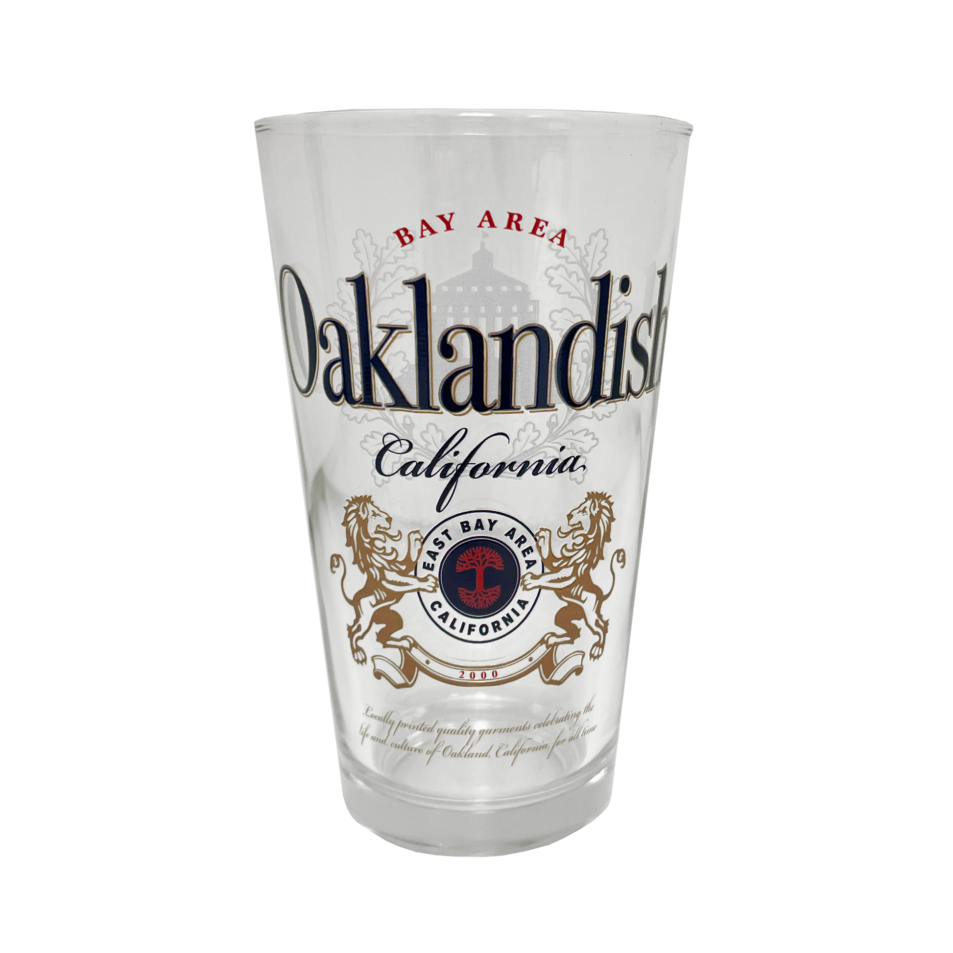 The Oaklandish Lager Pint Glass boasts a bold, ornate design with "Bay Area Oaklandish California" text. This 16 oz pint glass features a crest adorned with two golden lions facing each other, encircling a tree with the text “East Bay Area California.” Intricate design elements flawlessly blend text and graphics.