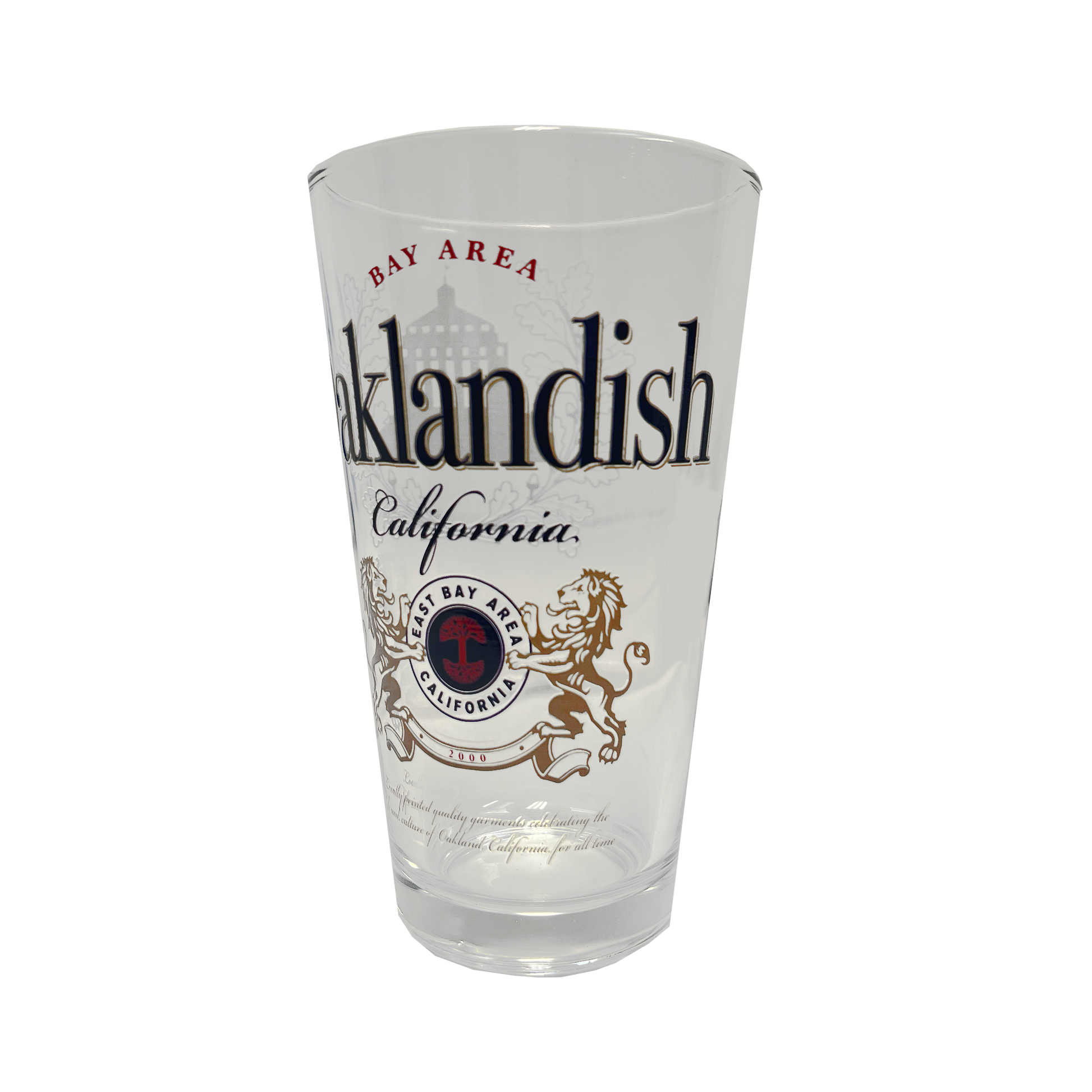 The **Lager Pint Glass** by **Oaklandish** is a stylish 16 oz pint glass featuring "Oaklandish" and "California" in bold black text. Above "Oaklandish," "Bay Area" is written in red, while below, a circular emblem displays "Bay Area California" flanked by two lions. The background of this practical drinkware is white, combining local pride with everyday functionality.